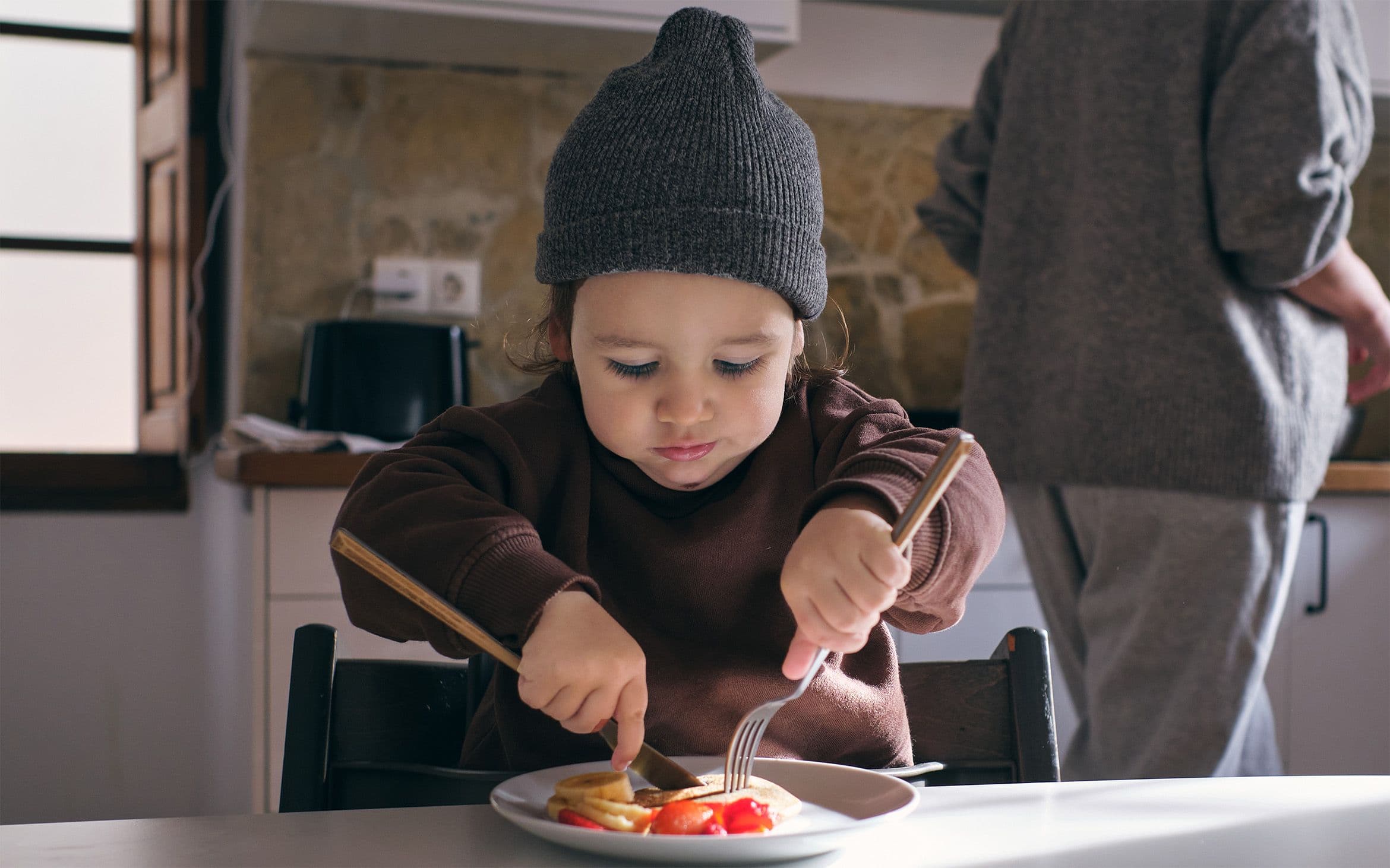 A child seated at a table with a meal